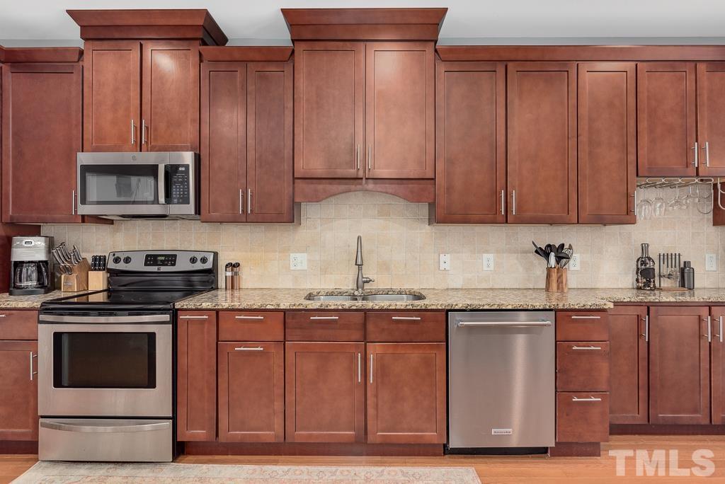 7030 Sandy Forks Road, Unit 103 Raleigh, NC 27615 - Photo 7 of 36 a kitchen with granite countertop wooden cabinets and stainless steel appliances