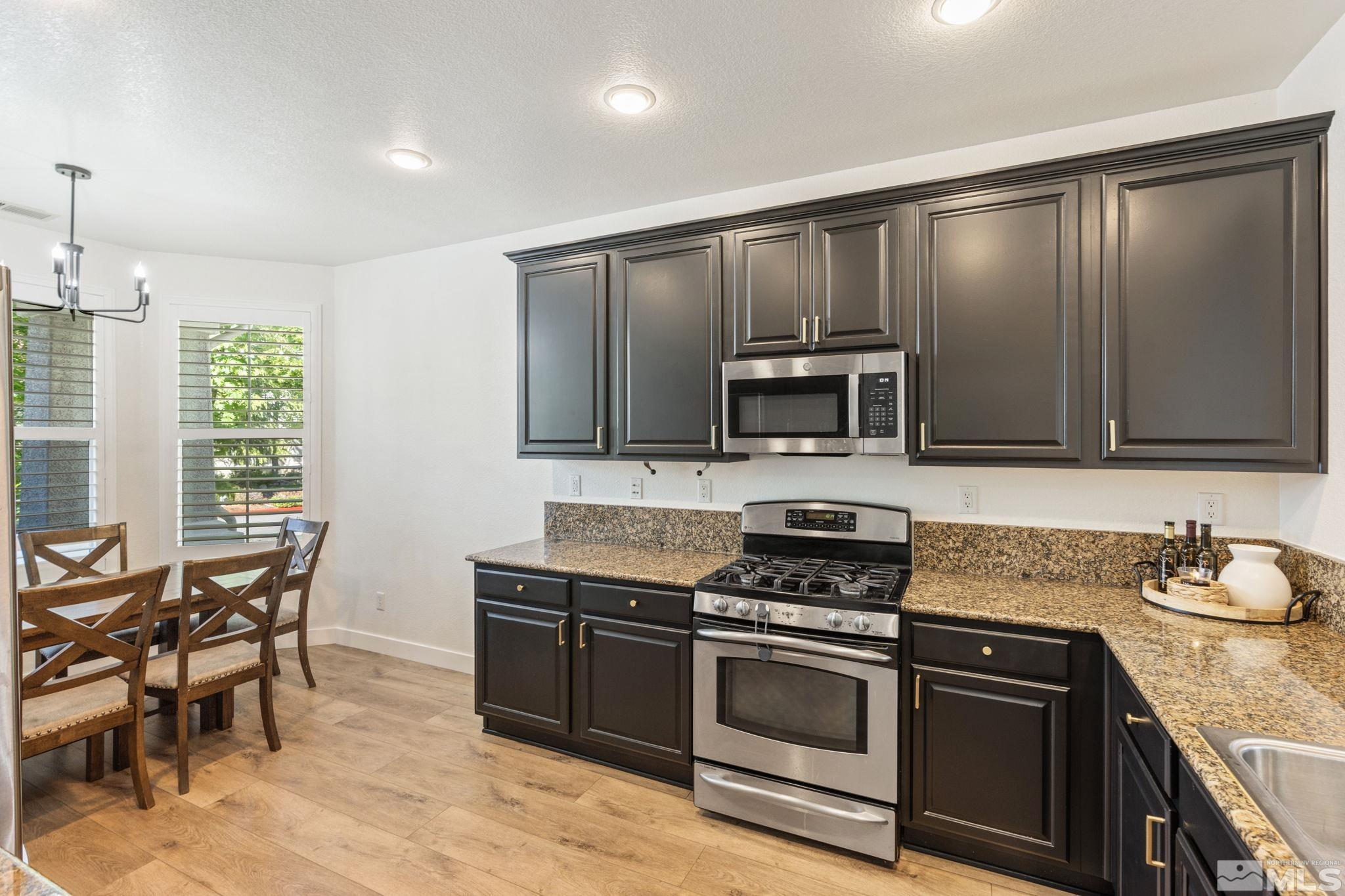 541 Needles Court Reno, NV 89521 - Photo 2 of 35 a kitchen with granite countertop wooden cabinets dining table and stainless steel appliances