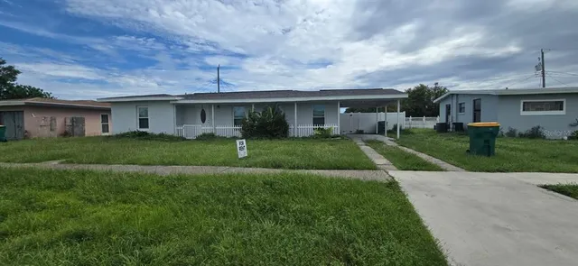 a view of a house next to a big yard and large trees