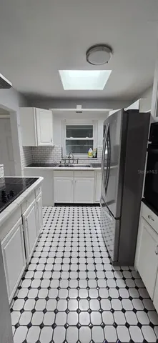 a kitchen with a sink a refrigerator and cabinets