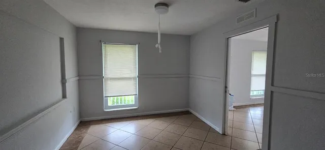 a view of an empty room with window and wooden floor