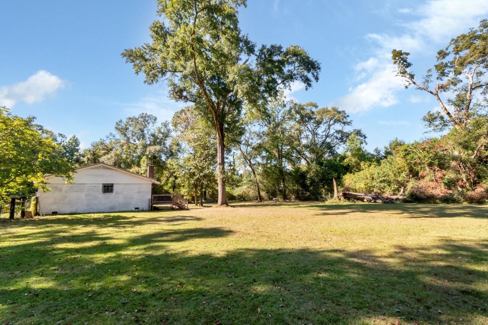 6405 1st Street Wilmer, AL 36587 - Photo 31 of 38 View of green lawn featuring a wooden deck and view of scattered trees