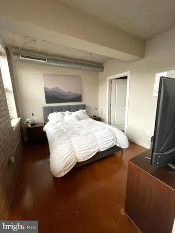 a bedroom with a bed and a flat tv screen on a dresser