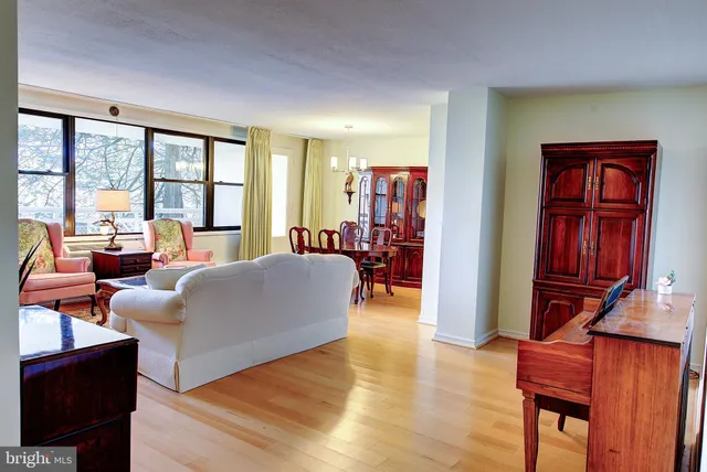 a living room with furniture a floor to ceiling window and wooden floor