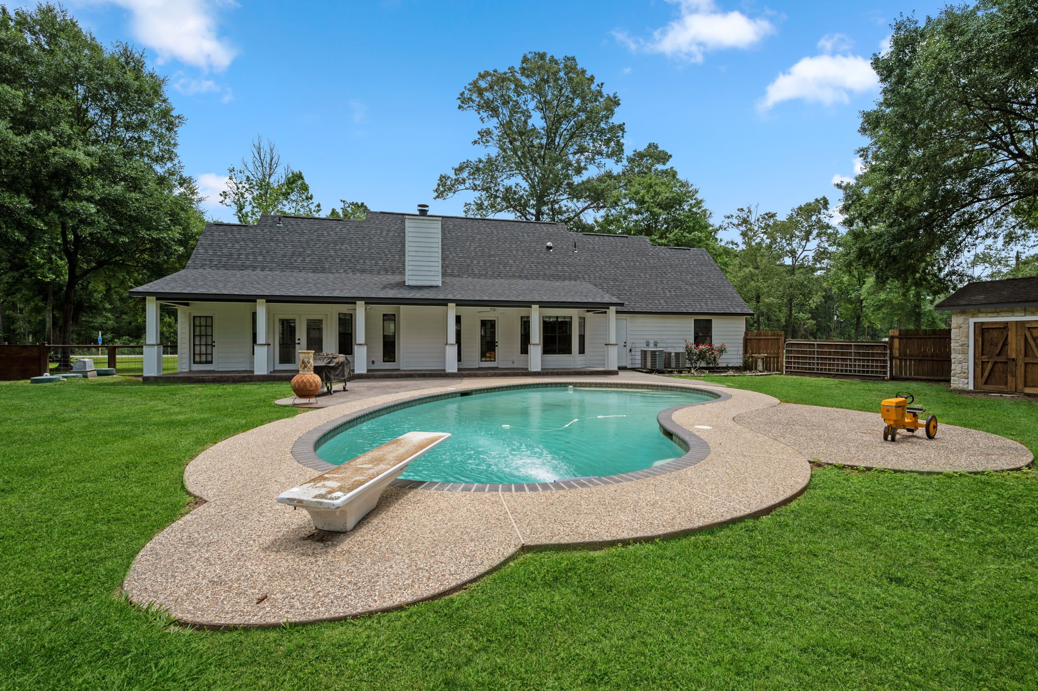 18 East Old Field Road Huffman, TX 77336 - Photo 26 of 35 Sweeping rear elevation showcasing the home’s impressive backyard oasis complete with sparkling pool, expansive patio areas, & lush green space ideal for entertaining and outdoor enjoyment.
