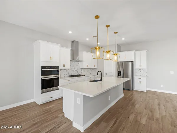 a large white kitchen with a stove a sink dishwasher and a refrigerator with wooden floor