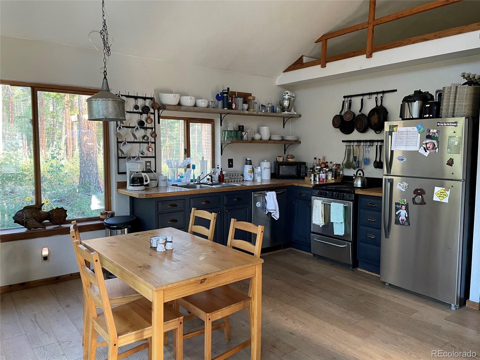 69 County Road 114 Bailey, CO 80421 - Photo 3 of 34 a kitchen with stainless steel appliances kitchen island granite countertop a table chairs in it and wooden floors