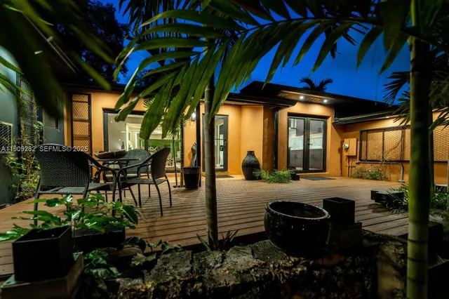 a view of a patio with table and chairs potted plants and large tree