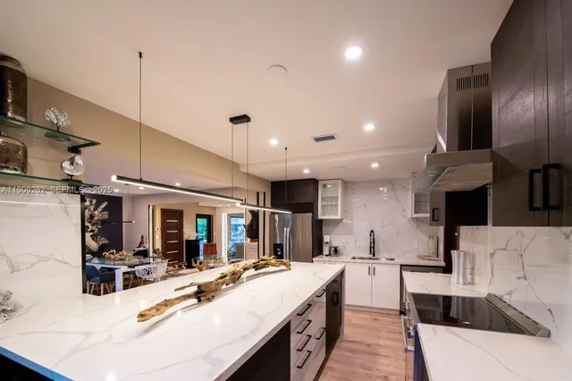 a large kitchen with stainless steel appliances kitchen island a large counter top a stove a sink and a refrigerator