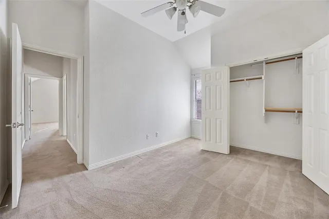 a view of an empty room with a chandelier fan