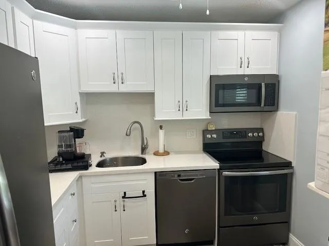 a kitchen with granite countertop white cabinets and black stainless steel appliances