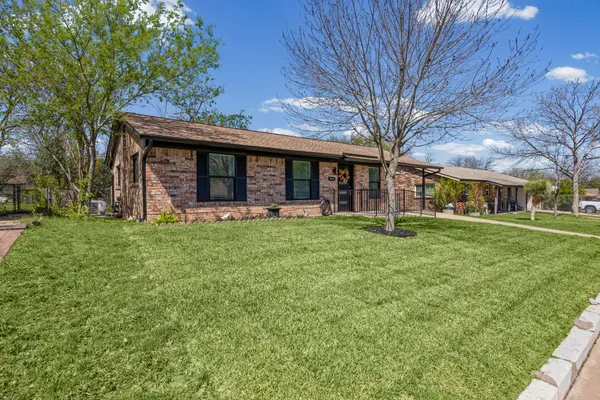 a view of a yard in front of a brick house with a large tree