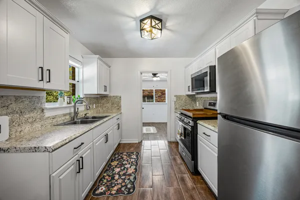 a kitchen with granite countertop stainless steel appliances a sink stove top oven and wooden floor