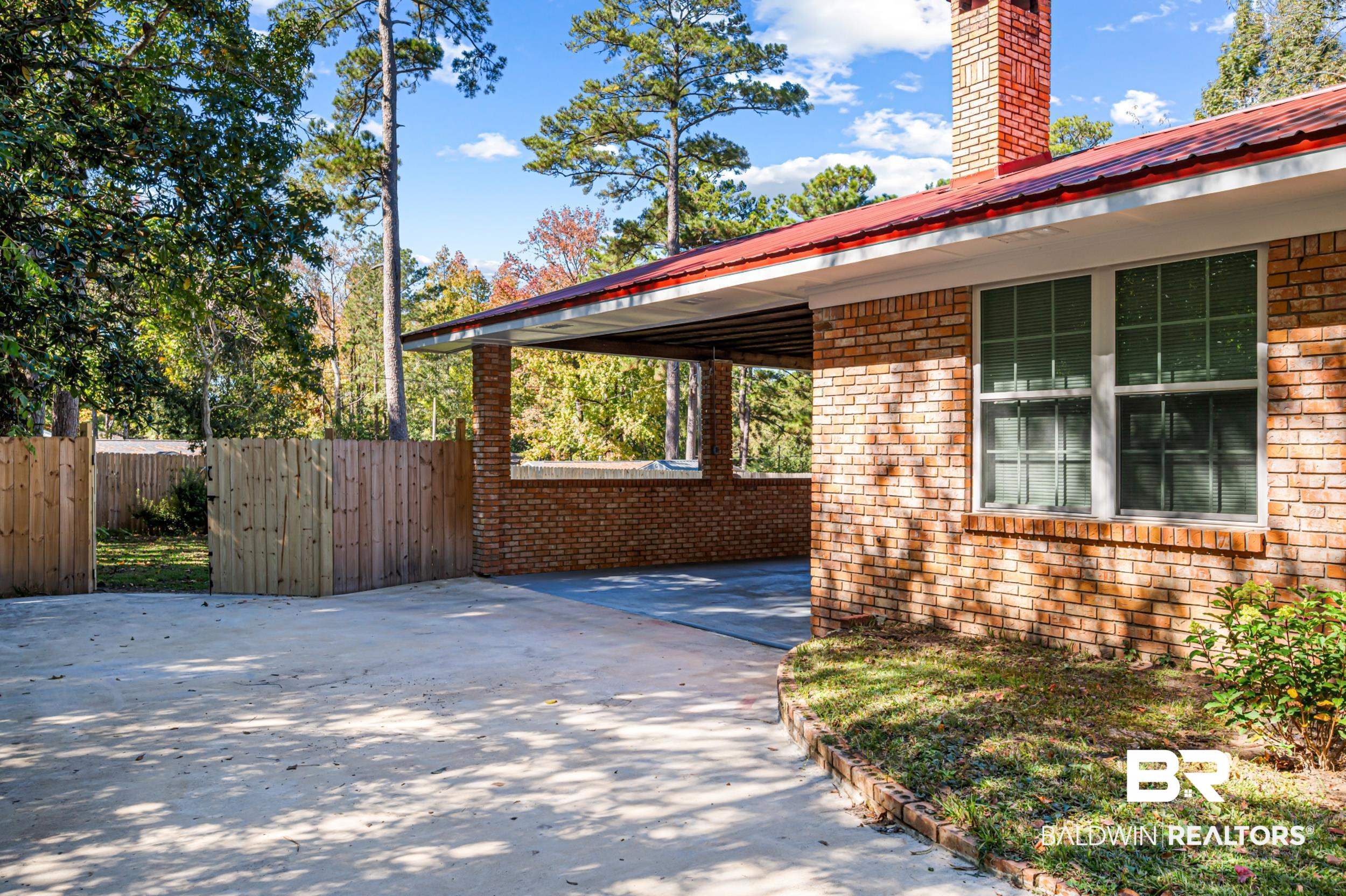 1605 Collier Avenue Bay Minette, AL 36507 - Photo 32 of 36 View of home's exterior featuring a metal roof, brick siding, a chimney, and concrete driveway