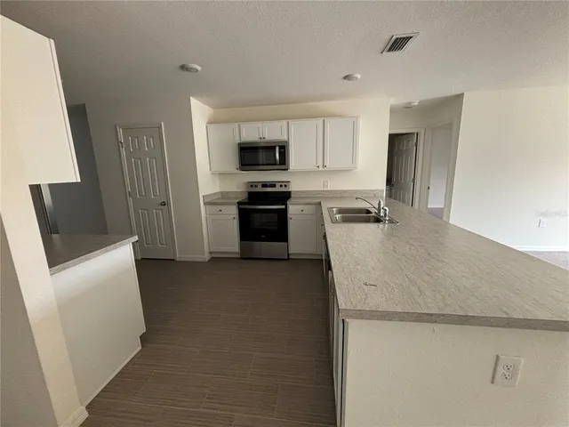 a kitchen with a sink a stove top oven a refrigerator and white cabinets