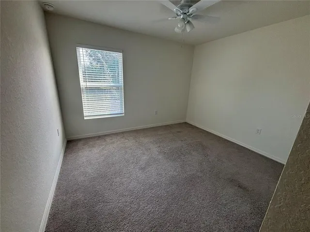 an empty room with a ceiling fan and window