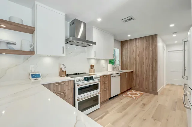 a kitchen with stainless steel appliances a stove a sink and white cabinets