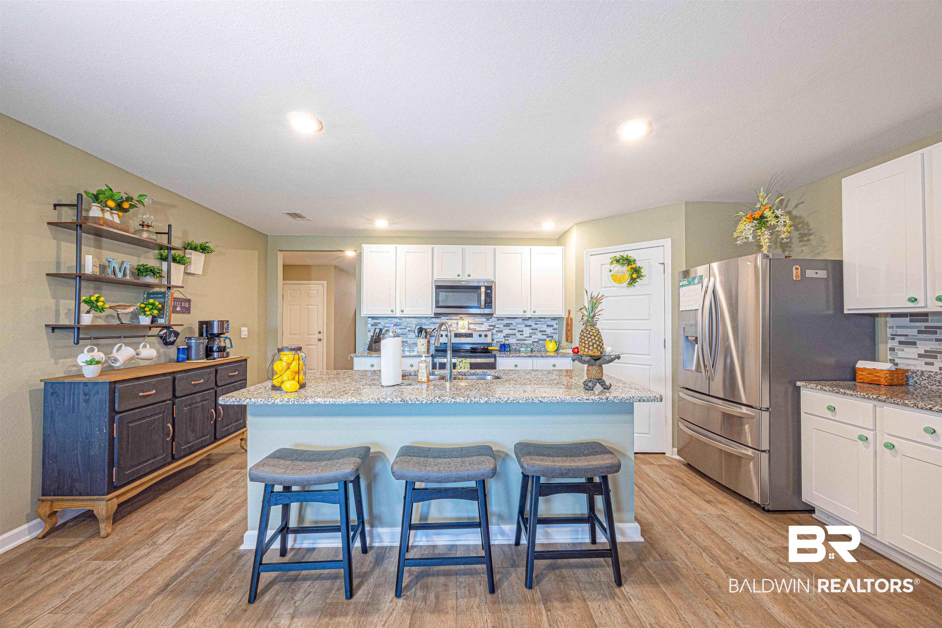 14843 Forsythia Loop Silverhill, AL 36576 - Photo 14 of 51 Kitchen with a breakfast bar, white cabinets, a kitchen island with sink, stainless steel appliances, and light stone counters