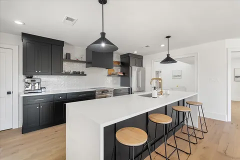 a kitchen with stainless steel appliances a sink a stove a refrigerator a dining table and chairs