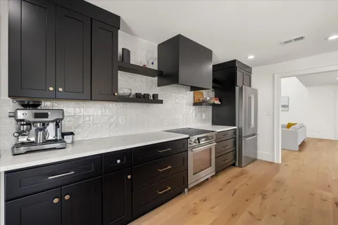 a kitchen with stainless steel appliances granite countertop a sink a stove a refrigerator and cabinets