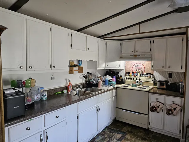 a kitchen with cabinets a sink and white appliances