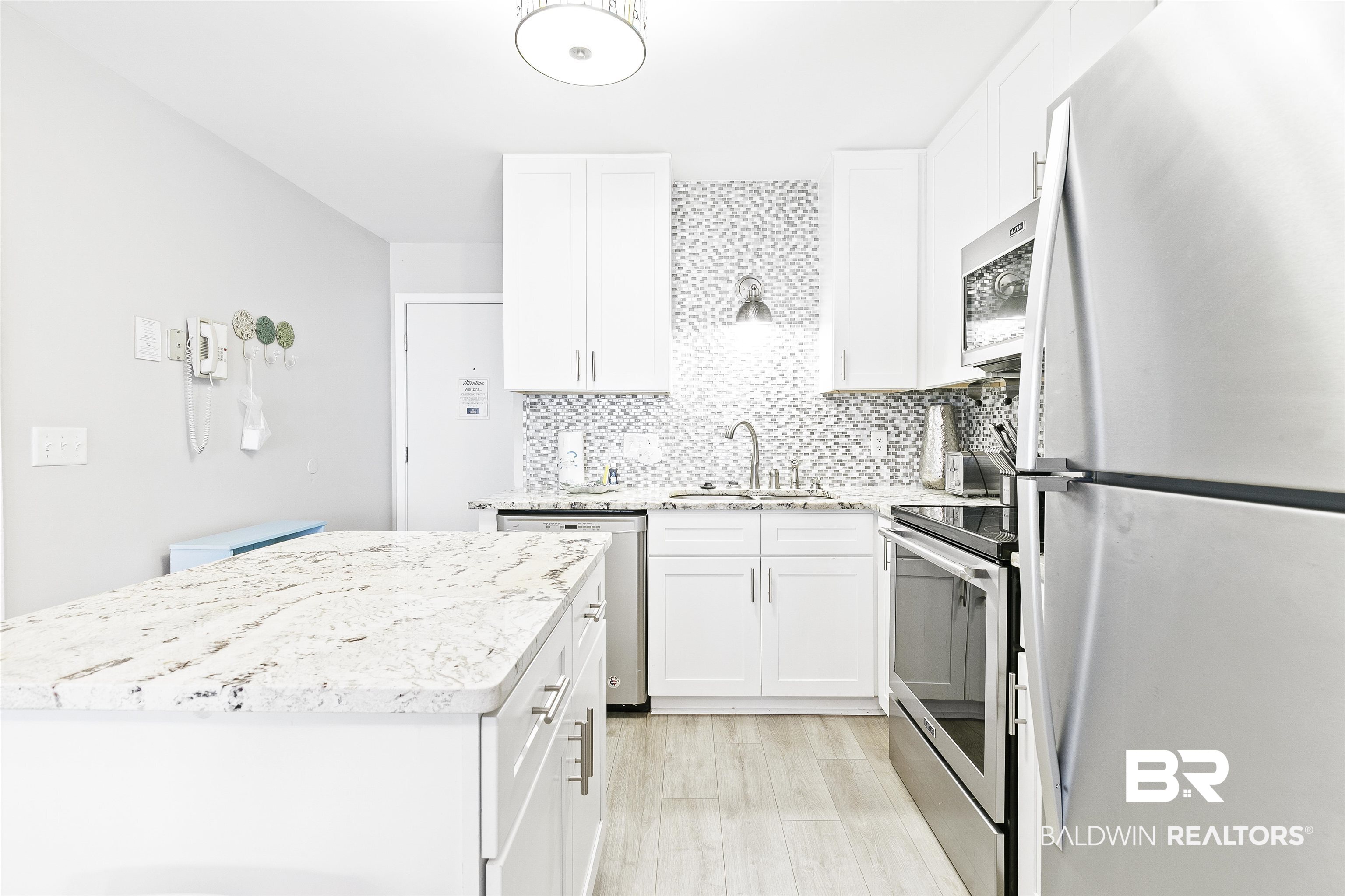 400 Plantation Road, Unit 3314 Gulf Shores, AL 36542 - Photo 11 of 47 Kitchen featuring white cabinets, sink, light stone countertops, appliances with stainless steel finishes, and tasteful backsplash