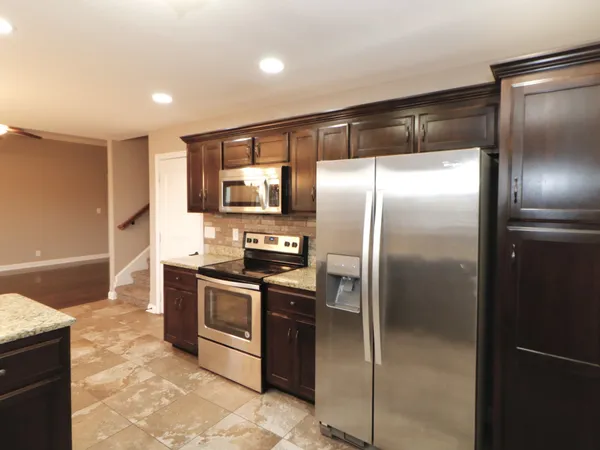 a modern kitchen with stainless steel appliances granite countertop a refrigerator and a sink