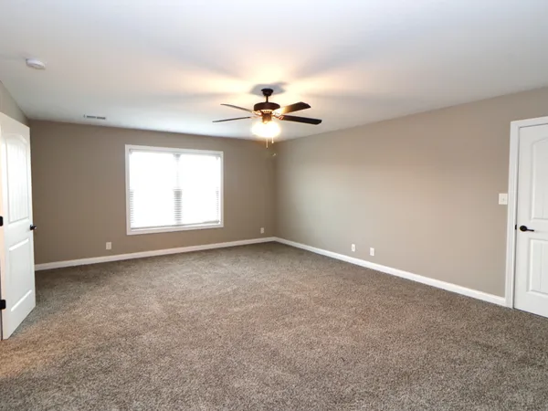 an empty room with windows and chandelier fan