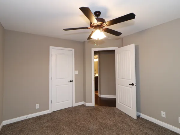 an empty room with closet and a chandelier fan