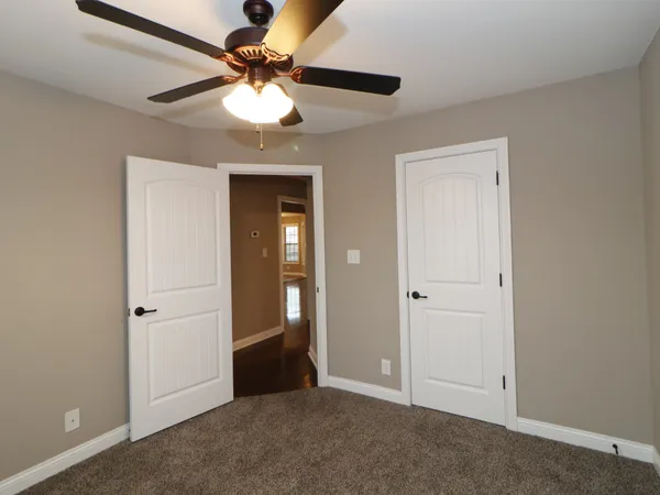 an empty room with closet and a chandelier fan
