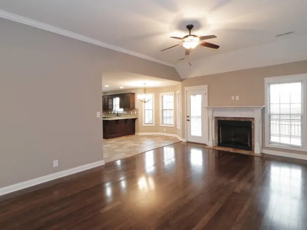 a view of an empty room with wooden floor and a fireplace