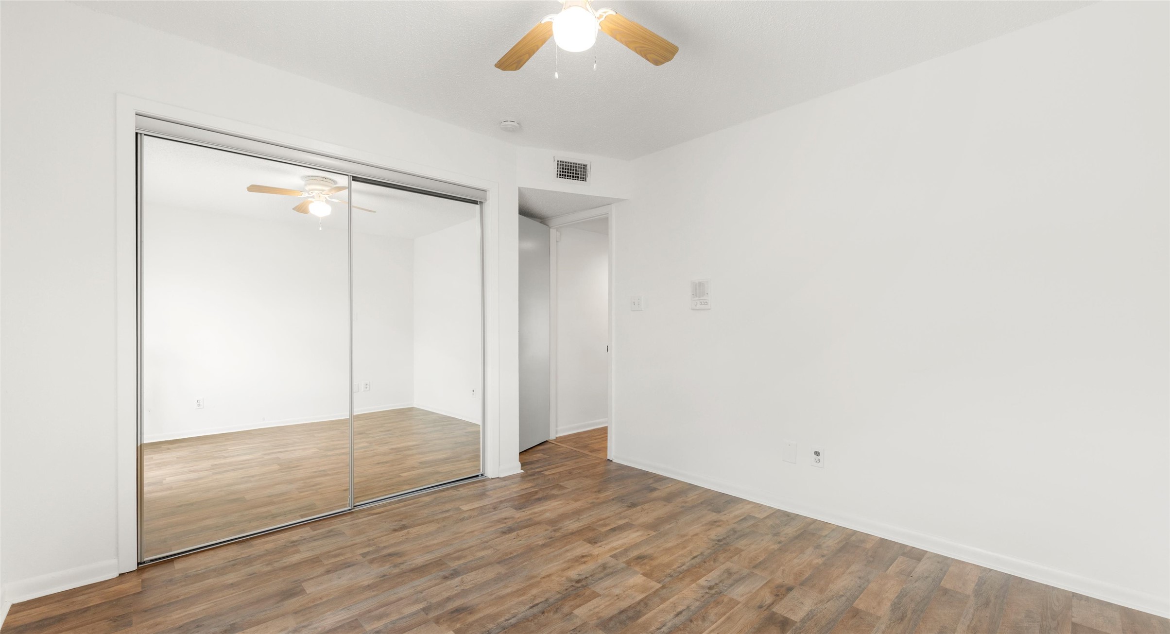 2918 Ranch Road 620 North, Unit C122 Austin, TX 78734 - Photo 11 of 36 This room features wood-look flooring, a ceiling fan with integrated lighting, and mirrored sliding closet doors