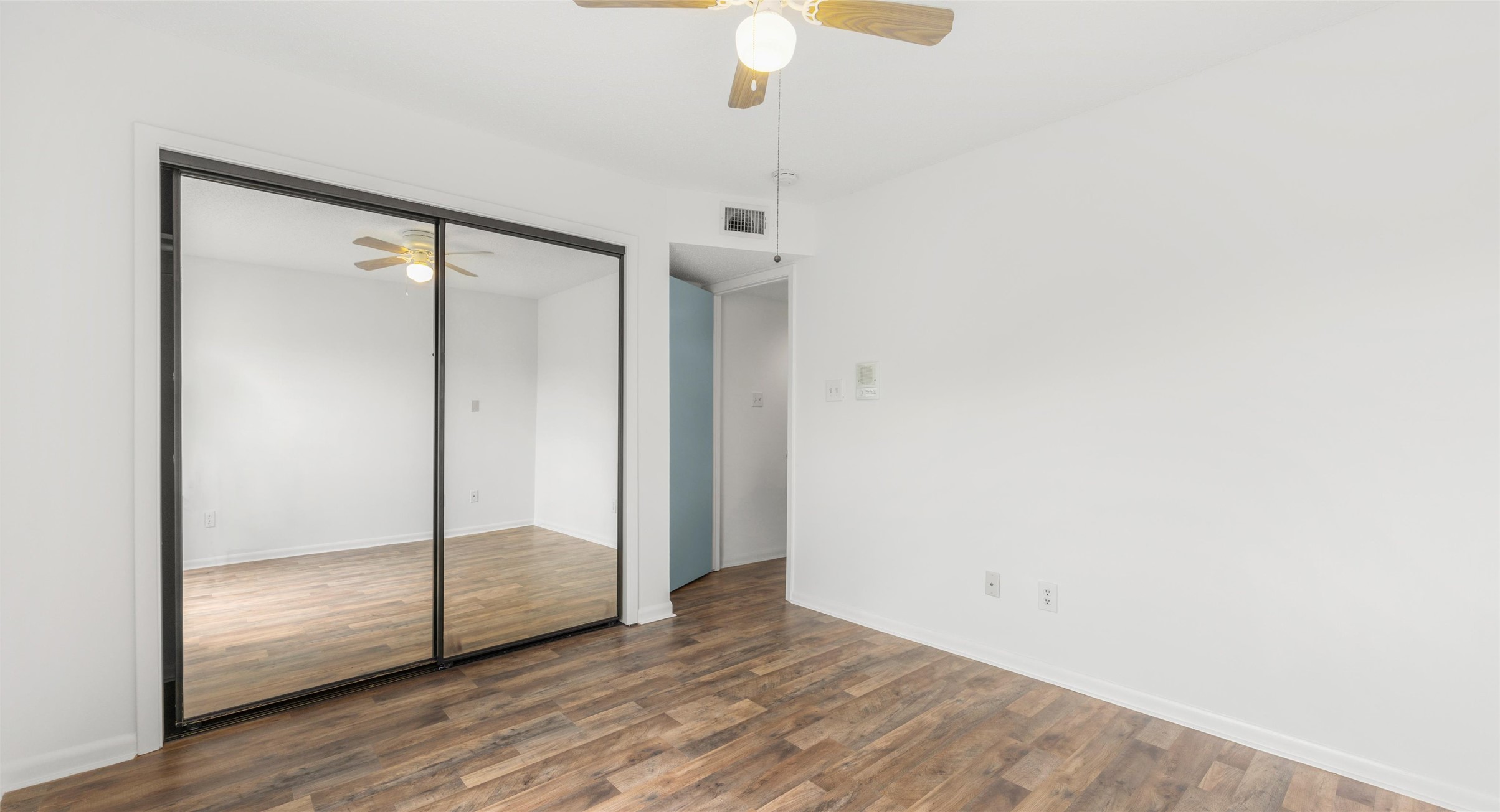 2918 Ranch Road 620 North, Unit C122 Austin, TX 78734 - Photo 15 of 36 Living area featuring wood-look flooring, white walls, a ceiling fan, and mirrored closet doors
