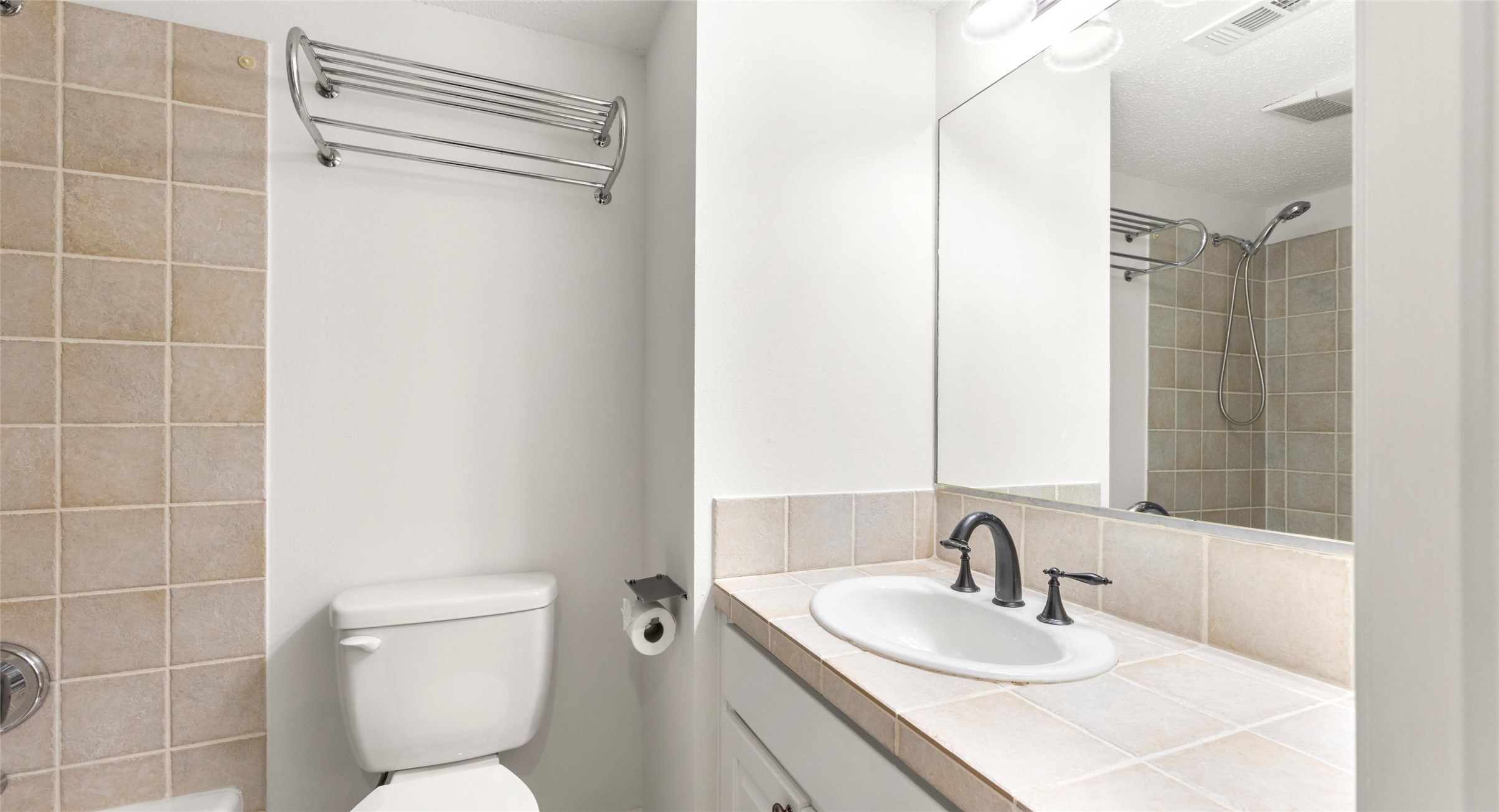2918 Ranch Road 620 North, Unit C122 Austin, TX 78734 - Photo 16 of 36 The bathroom features a tiled shower, a toilet, and a vanity with a sink and dark-toned faucet