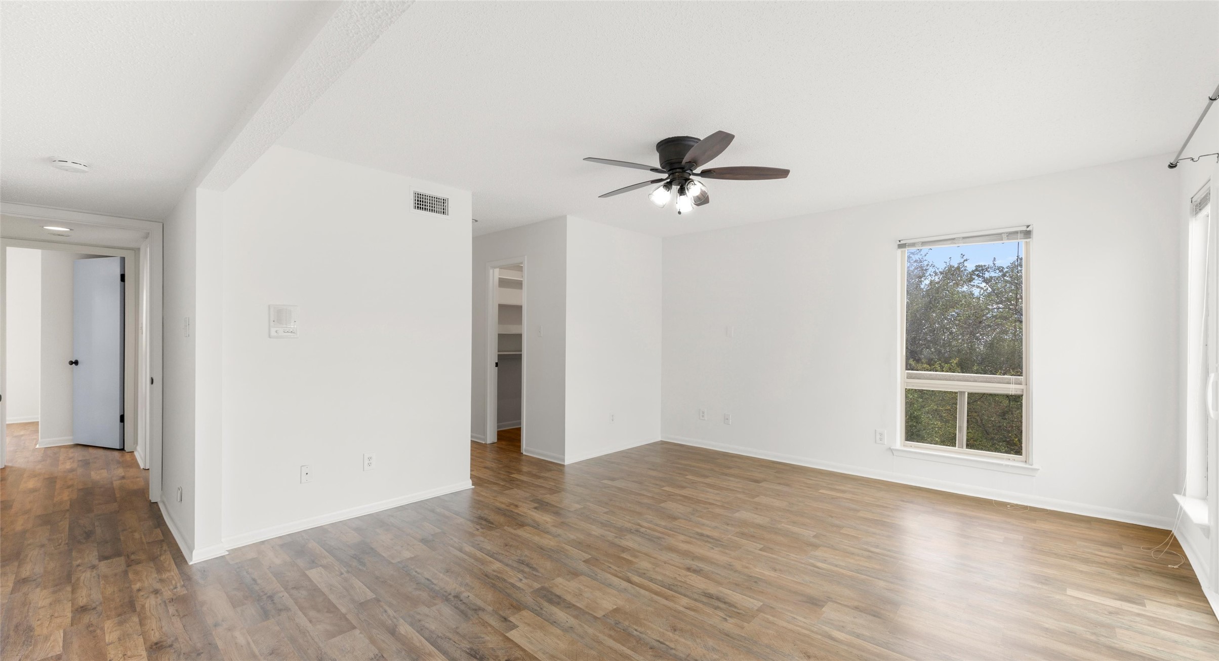 2918 Ranch Road 620 North, Unit C122 Austin, TX 78734 - Photo 17 of 36 Spacious living area featuring light-toned flooring, white walls, a ceiling fan with integrated lighting, and a large window providing views of outdoor foliage