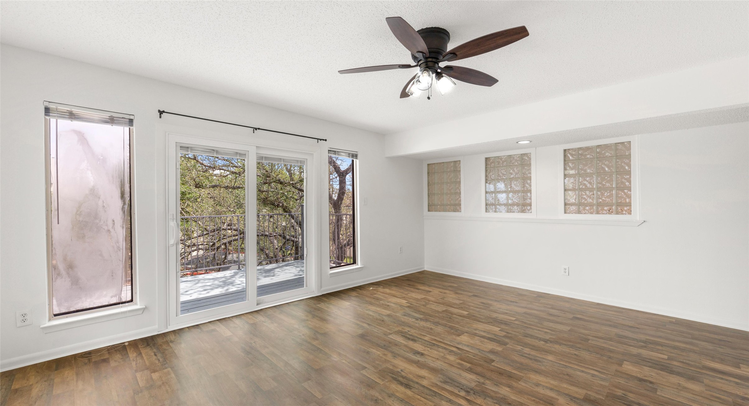 2918 Ranch Road 620 North, Unit C122 Austin, TX 78734 - Photo 18 of 36 Living area featuring wood-look flooring, white walls, a ceiling fan, and large sliding glass doors leading to a balcony