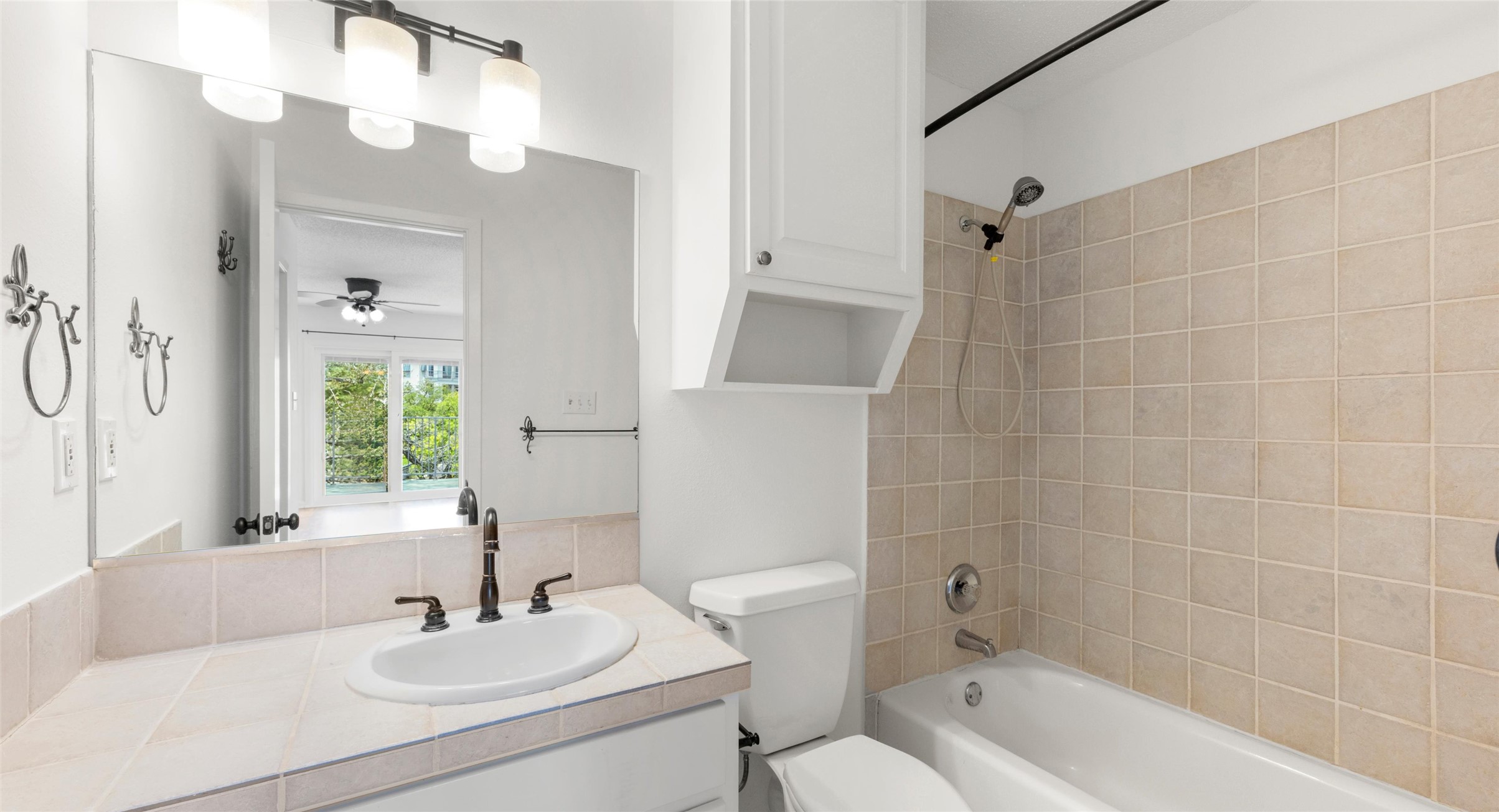 2918 Ranch Road 620 North, Unit C122 Austin, TX 78734 - Photo 19 of 36 Bathroom featuring a vanity with a white sink and dark bronze faucet, a mirror with a three-light fixture, and a shower-tub combination with tiled walls