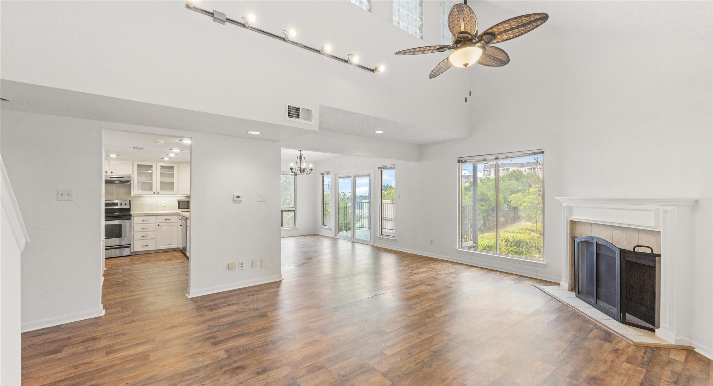 2918 Ranch Road 620 North, Unit C122 Austin, TX 78734 - Photo 2 of 36 The property features high ceilings, wood-look flooring, a fireplace with a white mantel, and large windows providing views of exterior greenery