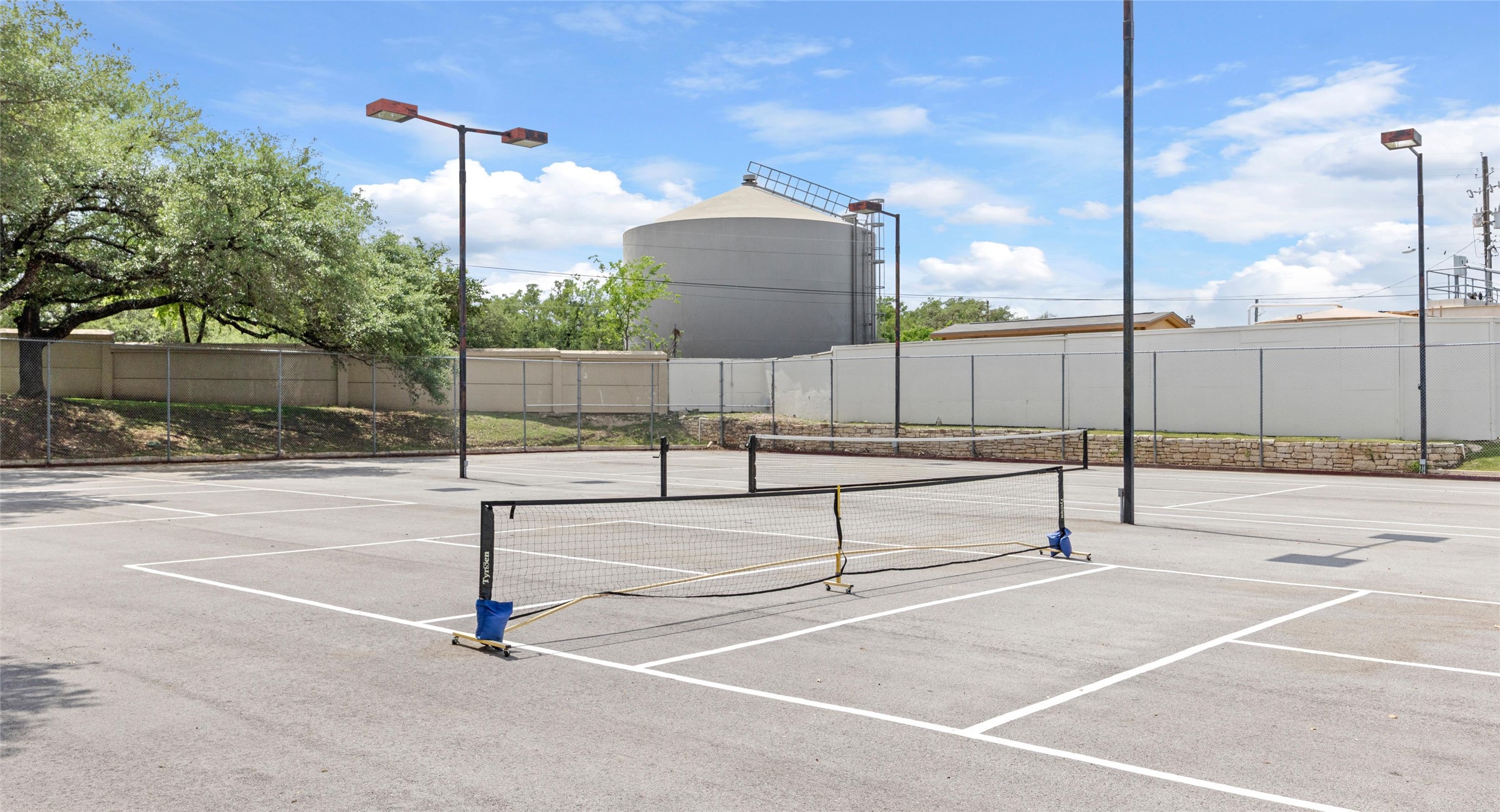 2918 Ranch Road 620 North, Unit C122 Austin, TX 78734 - Photo 24 of 36 Pickleball court with a paved surface and court lines, featuring a net and surrounding light poles