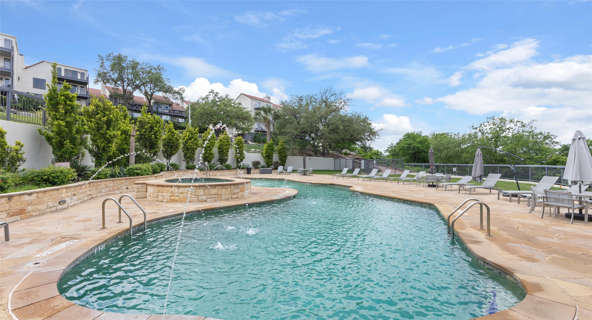 2918 Ranch Road 620 North, Unit C122 Austin, TX 78734 - Photo 26 of 36 The property features a large outdoor pool with a stone deck, integrated fountain features, and a separate stone-encased spa