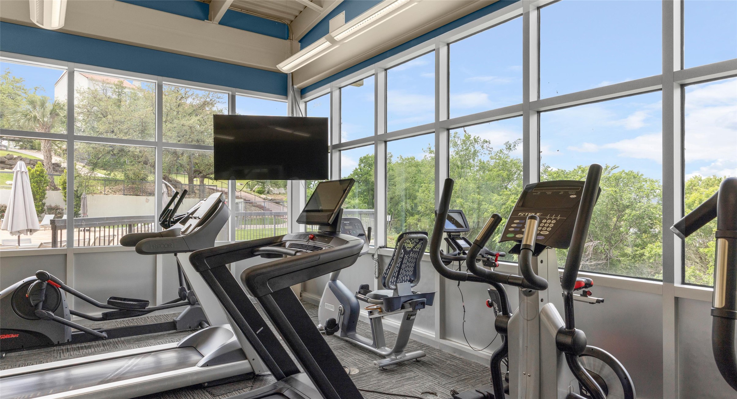 2918 Ranch Road 620 North, Unit C122 Austin, TX 78734 - Photo 27 of 36 The fitness area features large windows offering extensive views of the surrounding trees and property amenities, including a patio area with an umbrella