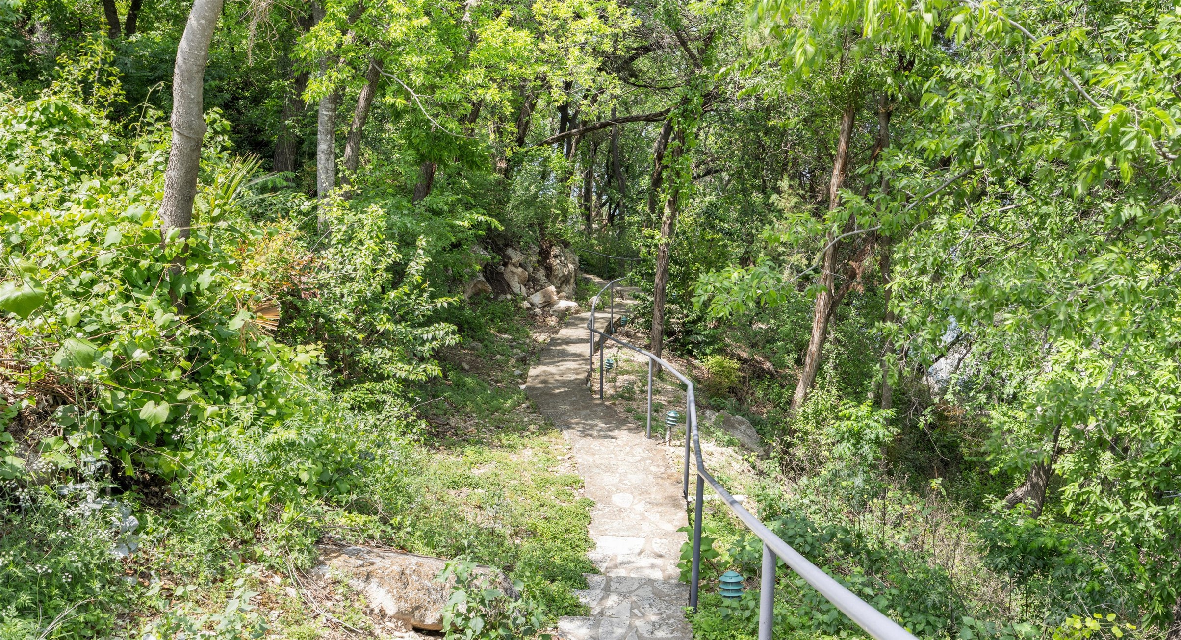 2918 Ranch Road 620 North, Unit C122 Austin, TX 78734 - Photo 28 of 36 The property features a stone pathway with handrails, surrounded by extensive greenery and mature trees