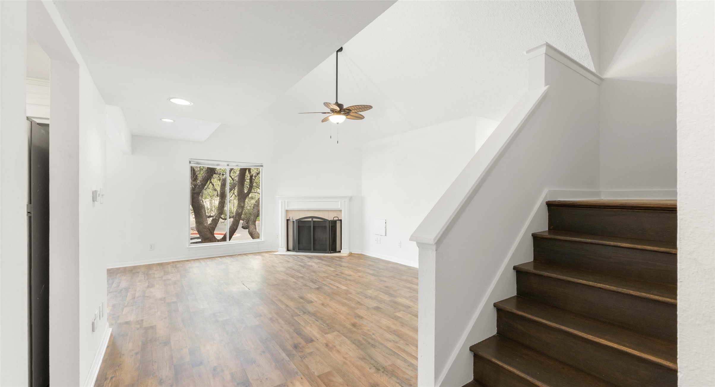 2918 Ranch Road 620 North, Unit C122 Austin, TX 78734 - Photo 5 of 36 The property features an inviting living area with rich wood flooring, a fireplace with a white mantel, and a large window offering views of mature trees