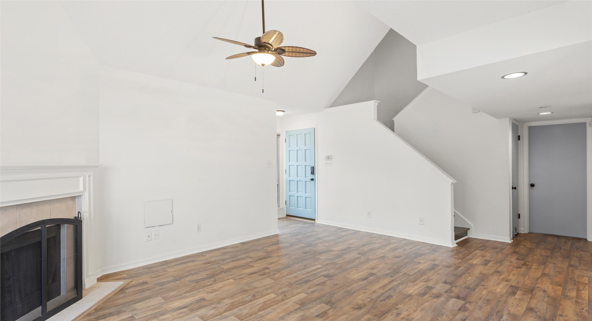 2918 Ranch Road 620 North, Unit C122 Austin, TX 78734 - Photo 7 of 36 Living area featuring wood-look flooring, a fireplace with a light-colored mantel, a ceiling fan with integrated lighting, and a light blue front door