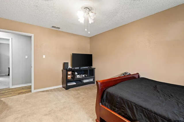 a bedroom with a bed and a flat tv screen on wall