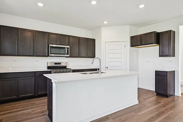 a kitchen with stainless steel appliances a stove top oven a sink a refrigerator and cabinets