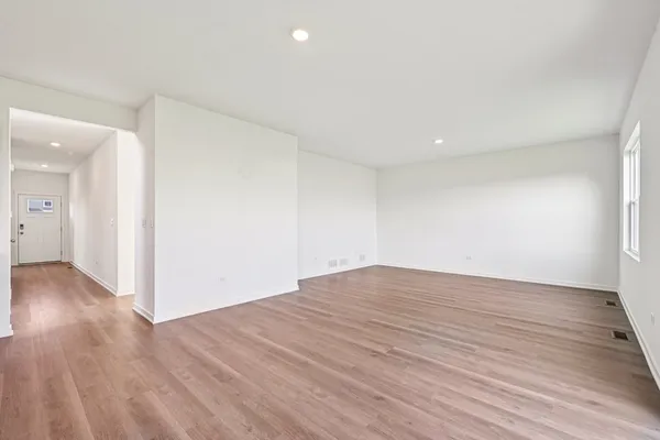 a view of an empty room with wooden floor and closet