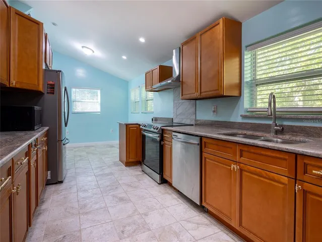 a kitchen with stainless steel appliances granite countertop wooden cabinets a sink and a stove