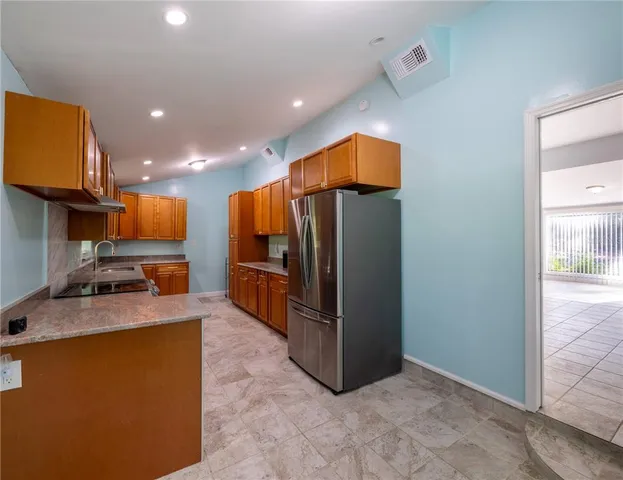 a kitchen with stainless steel appliances granite countertop a refrigerator a stove and a sink