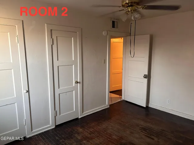 an empty room with wooden floor stairs and a chandelier fan